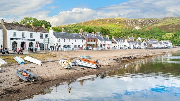 A coastal town with a row of white buildings, a sandy beach, and boats. - Harbour House Bed & Breakfast (Ullapool)