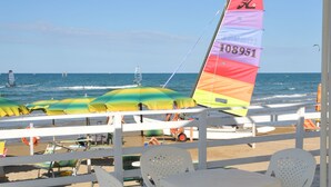 A beachside café with white plastic chairs and tables, a view of the sea, and colorful umbrellas. - Villaggio Le Orchidee (Vieste)