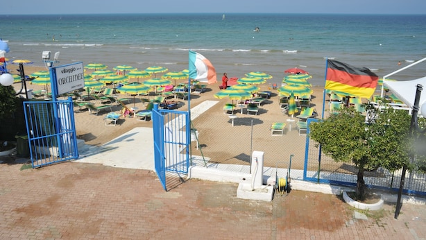 A beach with umbrellas, chairs, and a sign for 'Villaggio Orchidee'. - Villaggio Le Orchidee (Vieste)