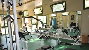 Une salle de sport équipée de divers appareils d’exercice, de bancs et d’haltères.