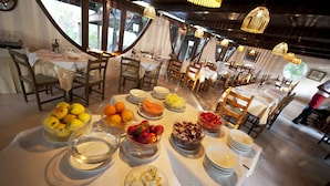 Un espace repas avec des tables rondes disposées pour accueillir plusieurs convives, où l’on peut admirer une variété de fruits et de plats présentés sur les tables.