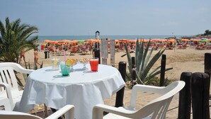 Un restaurant situé en bord de mer, avec une terrasse, une vue sur la plage et des parasols.