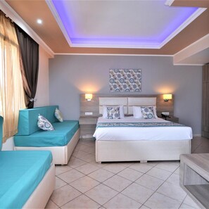A hotel room with a bed, a sofa, two bedside tables, and a ceiling with recessed lighting.