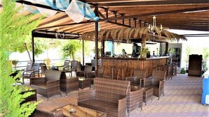 An outdoor bar area with wicker furniture and a thatched roof. - Grand Beach Hotel (Thasos)