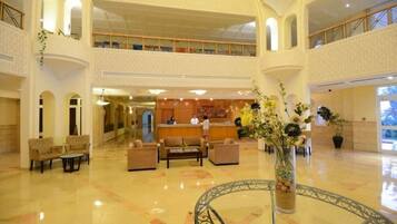 A spacious lobby with a reception desk, seating area, and a decorative vase with flowers.