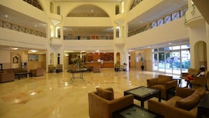 A spacious lobby with multiple seating areas, a reception desk, and a large window providing a view of the outside.