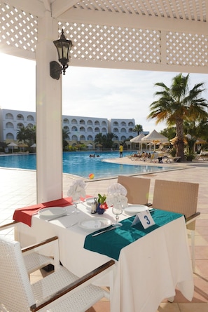Mesa lista para comer con vista a una piscina y edificios de un complejo turístico.
