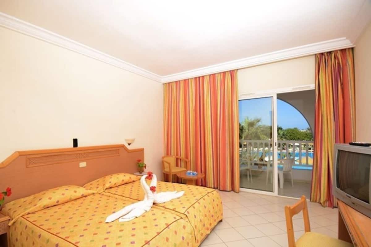 A hotel room with two beds, a TV, a small table, and a chair.