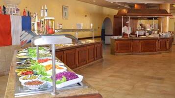 A buffet with various food options, a kitchen area, and a counter with a staff member.