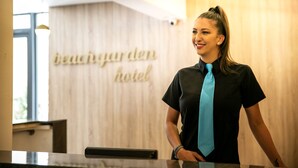 Ein Empfangsbereich mit einer Holzwand und einem Schild, auf dem 'beachgarden hotel' steht.