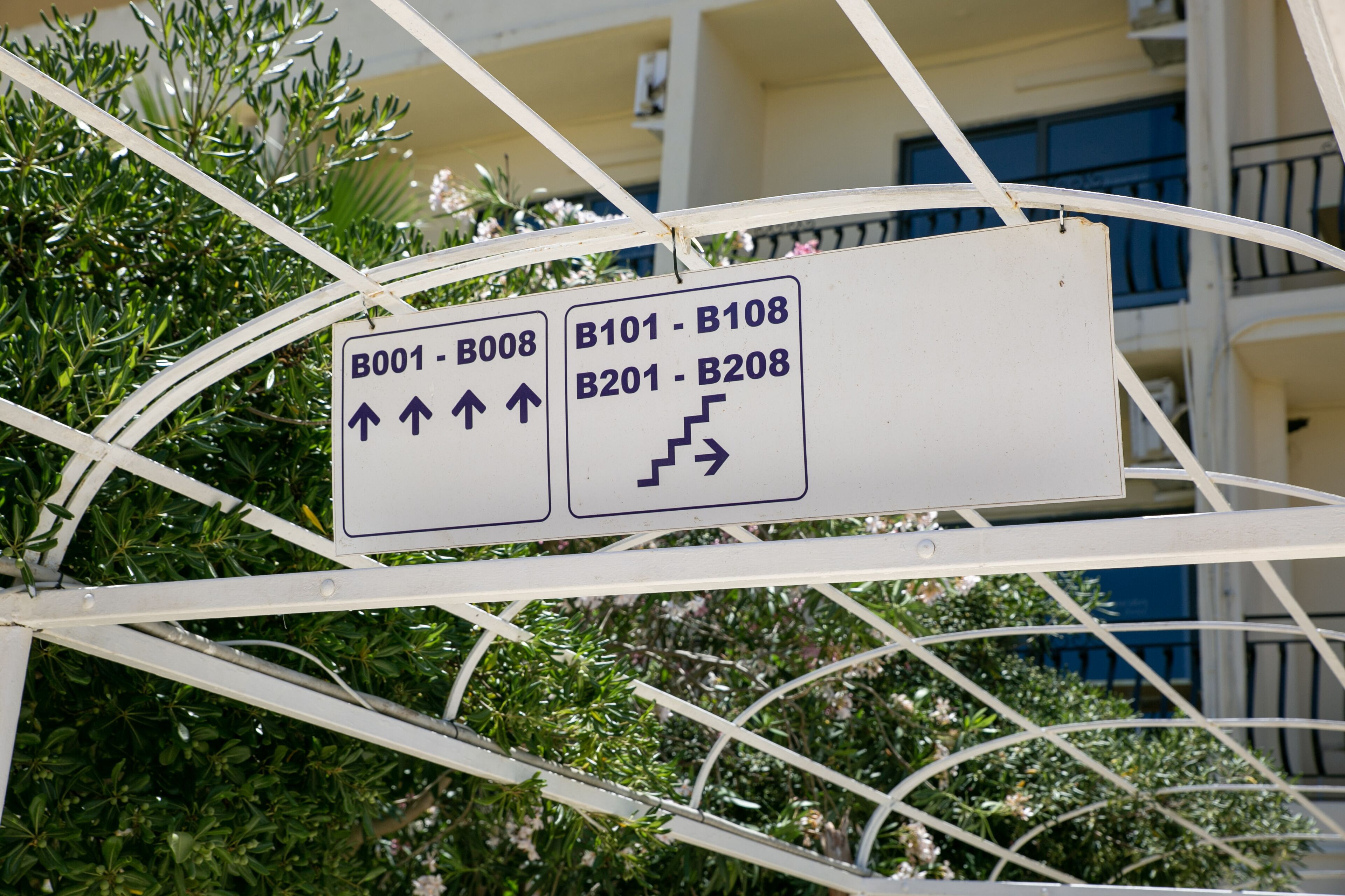 A directional sign with arrows indicating the way to various building numbers.