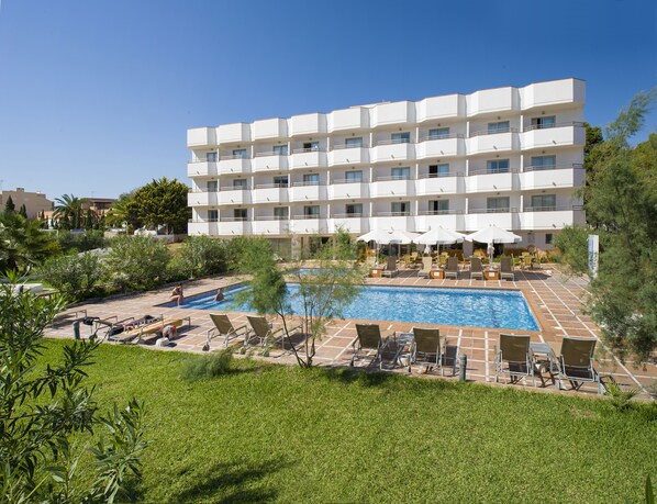 Un hôtel à plusieurs étages doté d’une piscine et d’un espace extérieur aménagé avec des sièges.
