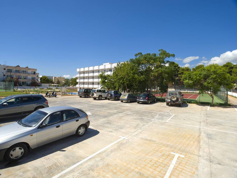 Ein Parkplatz mit mehreren Autos und einem Tennisplatz im Hintergrund.