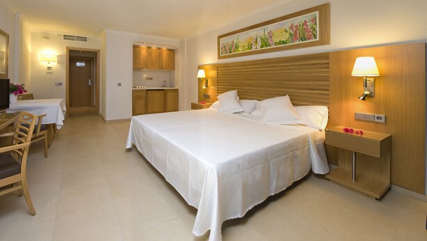 A hotel room with a bed, desk, chair, and a television.