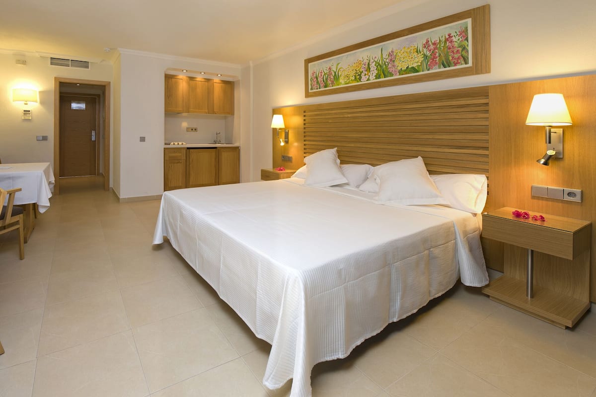 A hotel room with a bed, desk, chair, and a television.