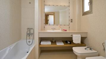 A bathroom with a bathtub, a sink, a toilet, and a mirror.