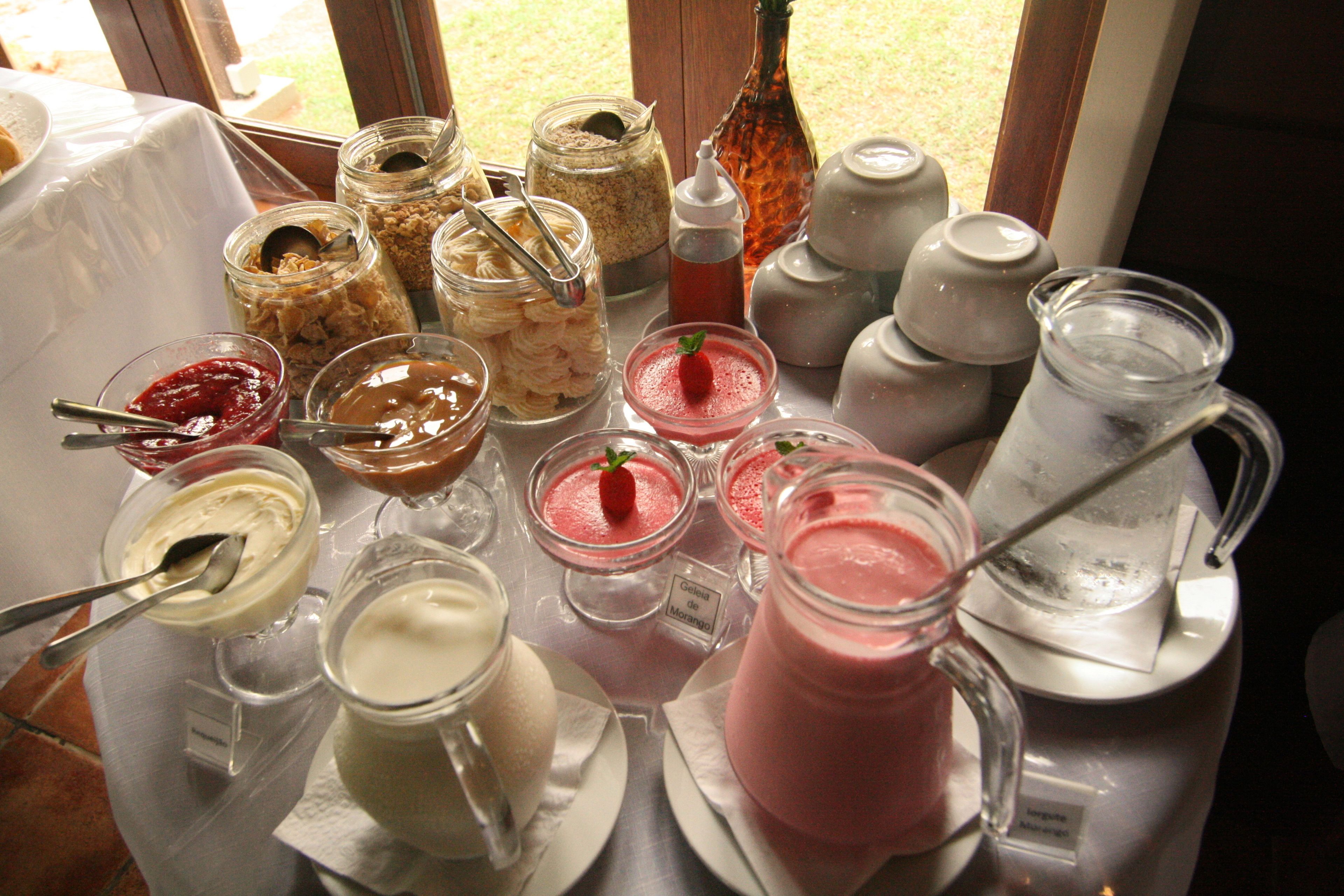 Variedad de opciones de comida y bebida, incluyendo botes de granola, tazones de yogur y una jarra de té helado.