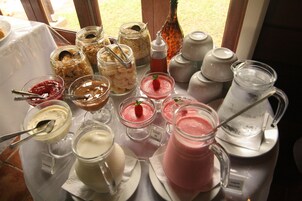 Variedad de opciones de comida y bebida, incluyendo botes de granola, tazones de yogur y una jarra de té helado.