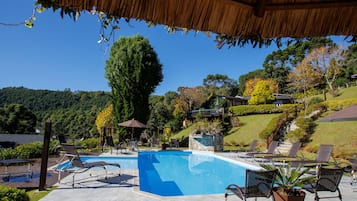 Una piscina techada, una piscina al aire libre, sombrillas