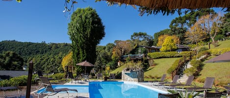 Una piscina techada, una piscina al aire libre, sombrillas