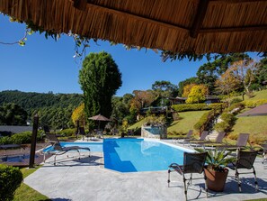 Una piscina techada, una piscina al aire libre, sombrillas