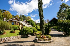 A house with a stone pathway leading to the entrance, surrounded by well-maintained gardens and trees. - Pousada Varanda das Colinas (Monte Verde)