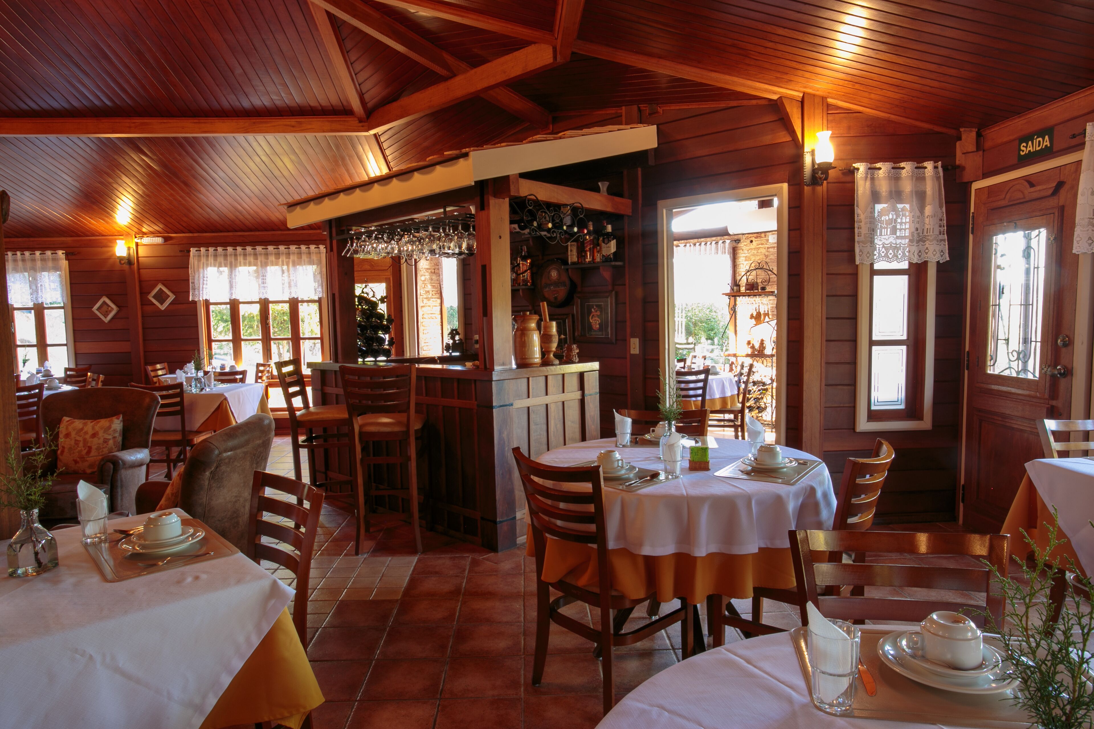 A restaurant with wooden interiors, multiple dining tables, and chairs.
