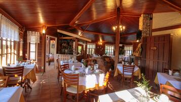 Um restaurante com interiores em madeira, várias mesas e cadeiras, e uma área de bar.