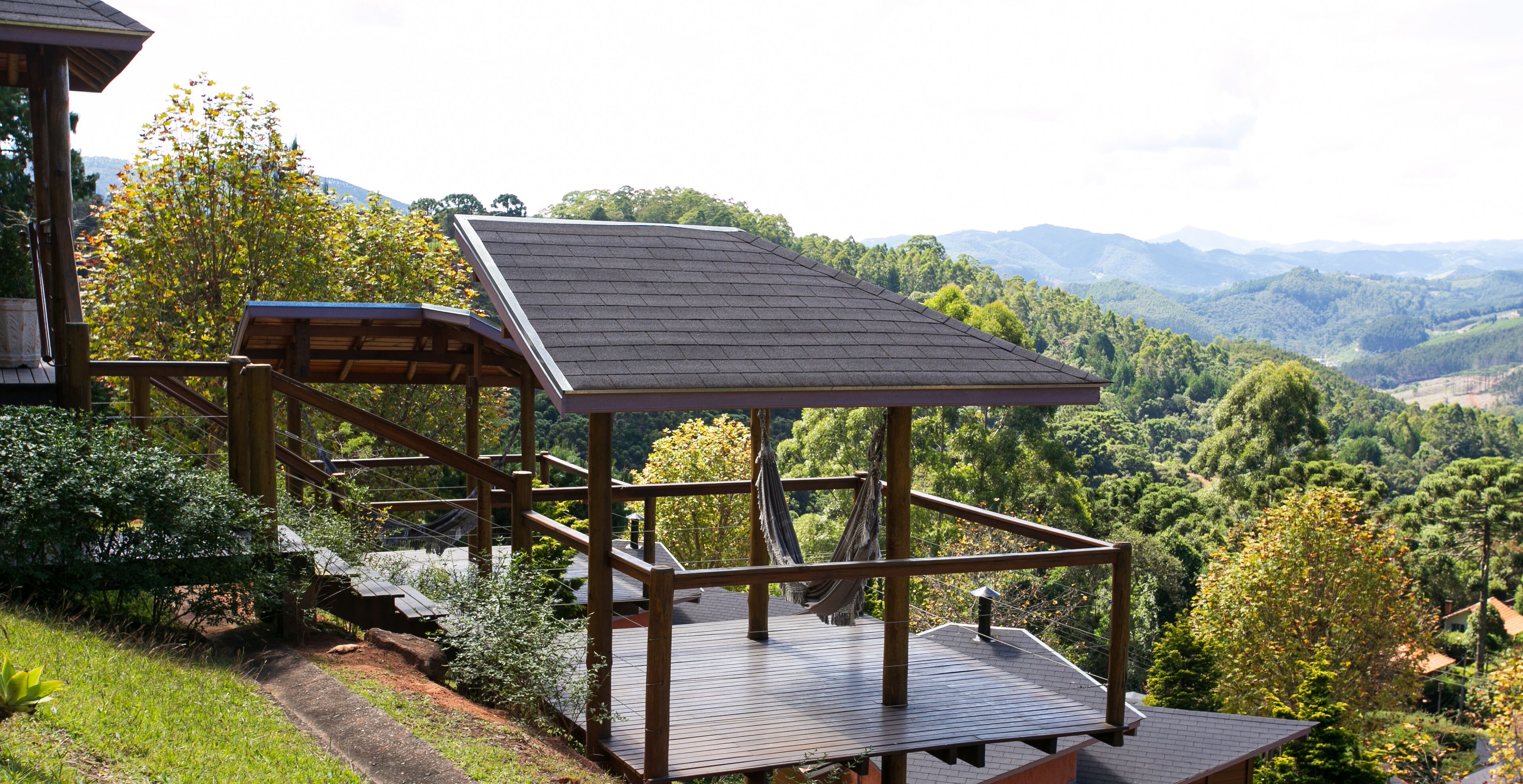 A wooden deck with a hammock and a view of a mountainous landscape.