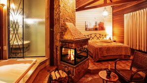 A cozy room with a stone fireplace, a bathtub, and a bed. - Pousada Varanda das Colinas (Monte Verde)