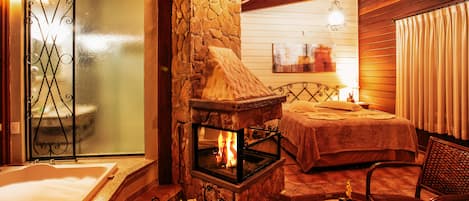 A cozy room with a stone fireplace, a bathtub, and a bed.