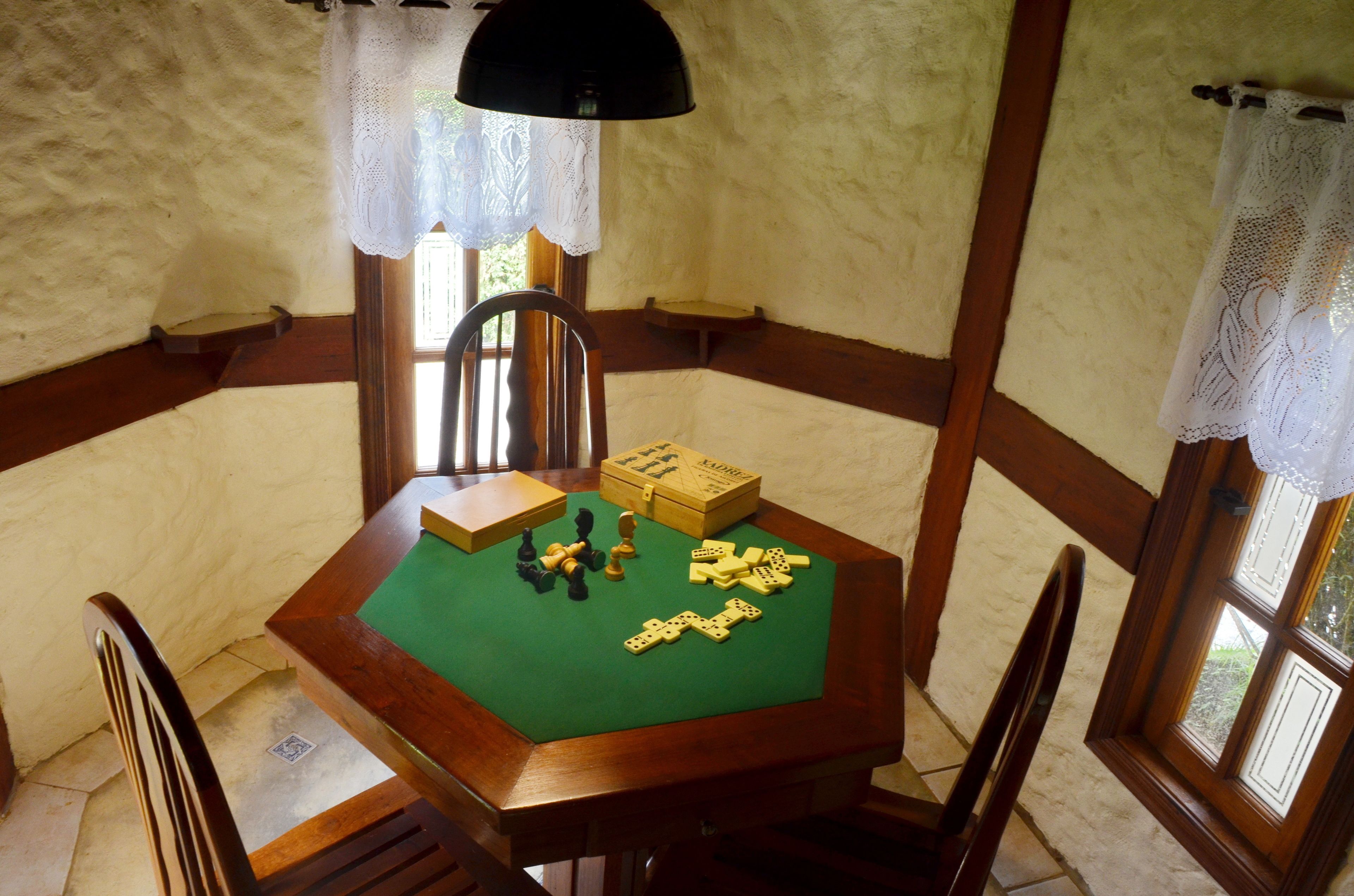 Una mesa de madera con superficie de fieltro verde, piezas de ajedrez y una caja de piezas de ajedrez.