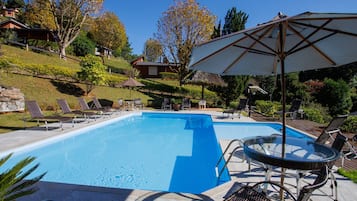 A rectangular swimming pool with clear blue water, surrounded by lounge chairs and a glass table.