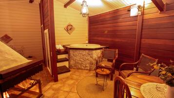 Une pièce chaleureuse avec un mur en pierre, un plafond en bois et une table ronde en bois, entourée de chaises.