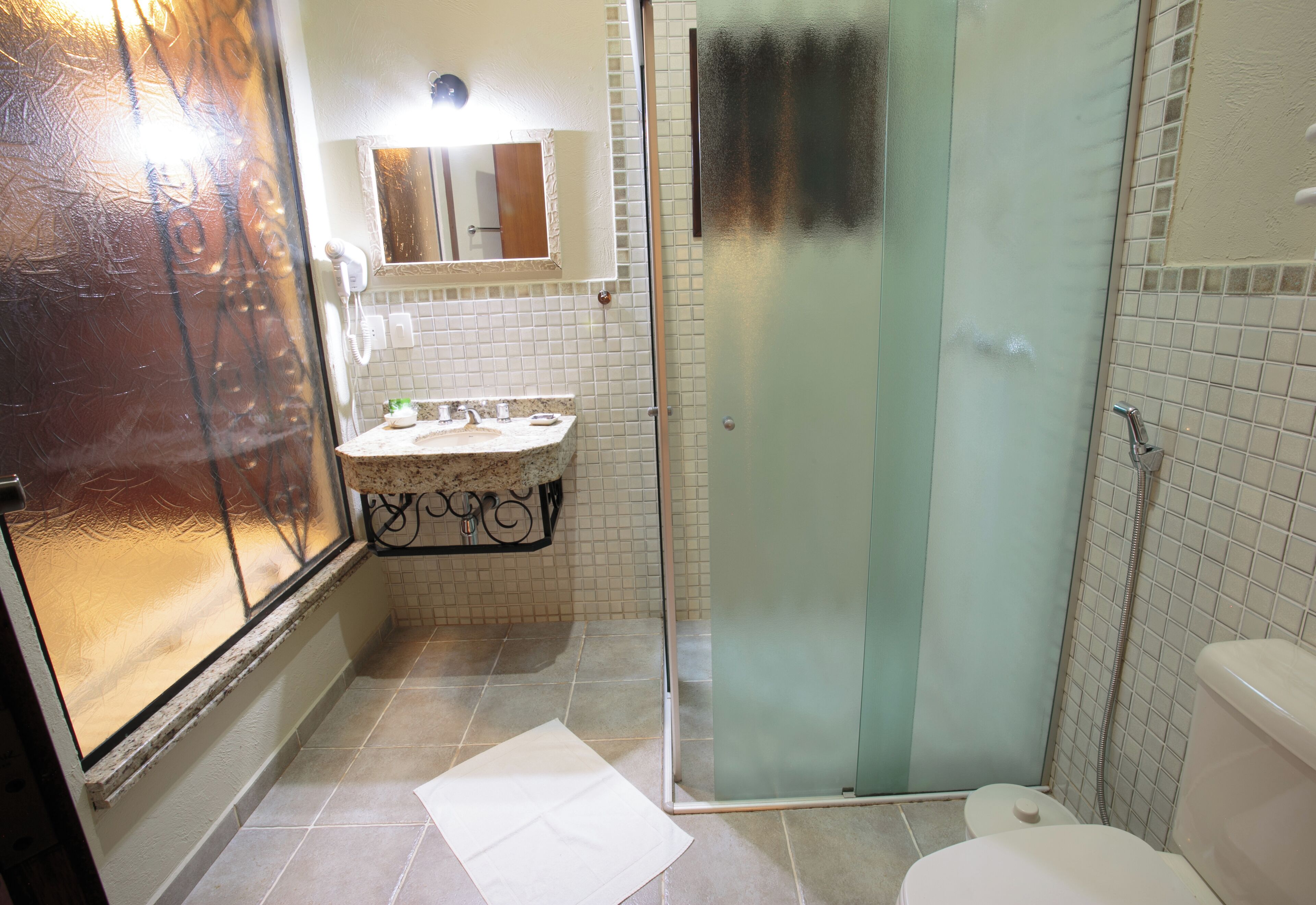 Un bagno con box doccia in vetro, un water bianco e un lavandino con specchio sopra.