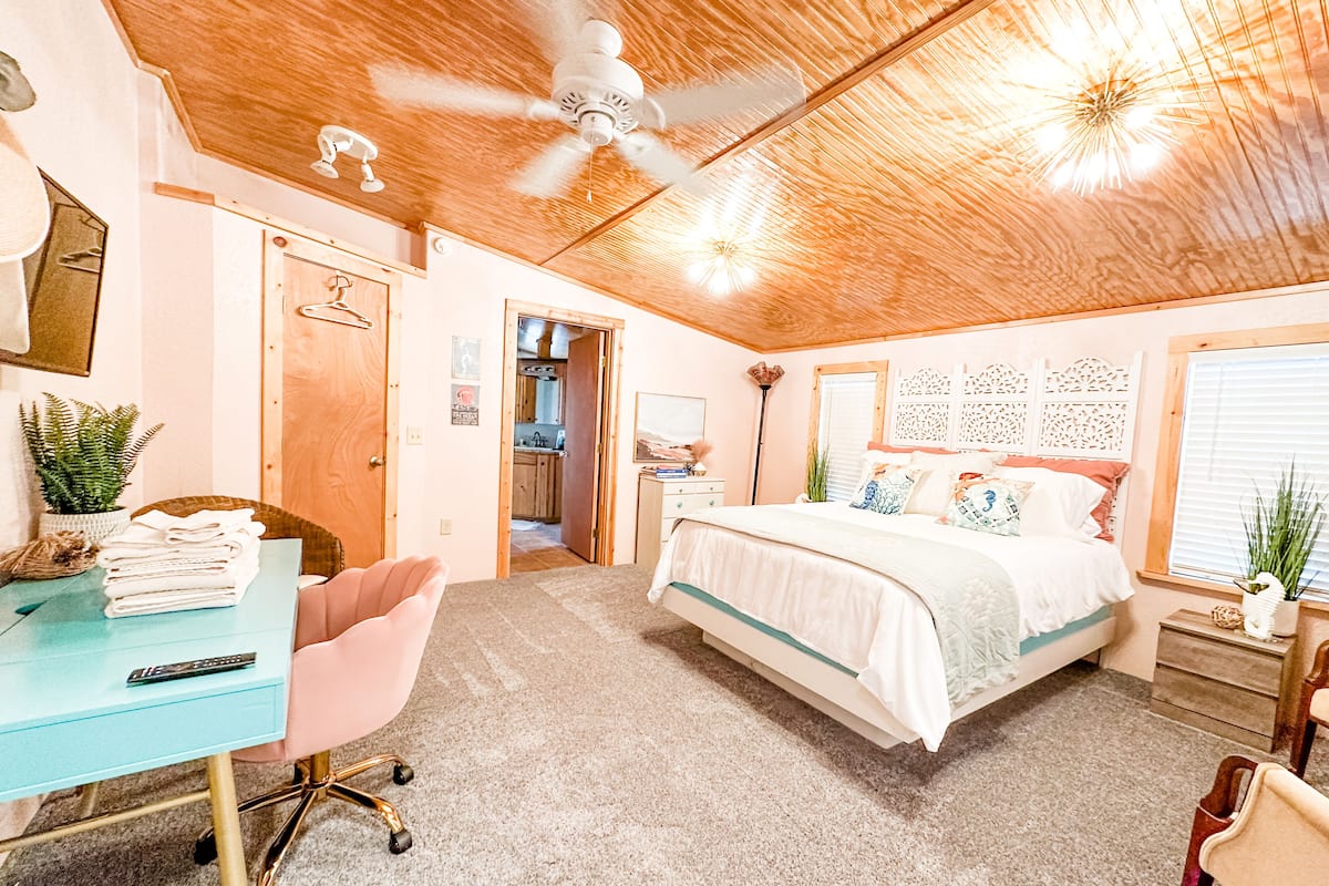 Une chambre à coucher comprenant un lit, un bureau, une chaise et un ventilateur de plafond.