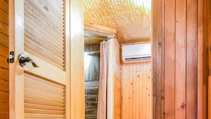 A wooden interior with a tiled floor, a wooden door, and a visible shower area. - Inn at the Art Center (San Angelo)
