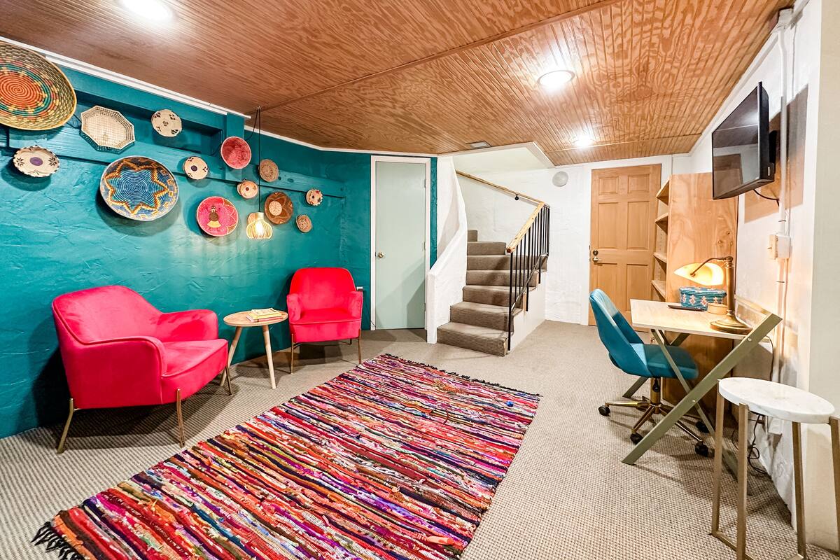 Une pièce chaleureuse avec un mur d’accent de couleur turquoise, un plafond en bois, un escalier et un petit coin repas.