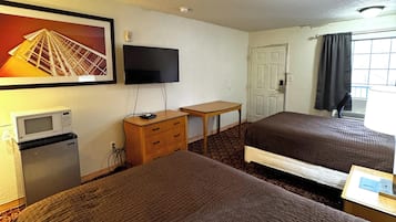 A hotel room with two beds, a television, a small desk, a microwave, and a refrigerator.