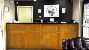 A reception desk with a logo, a computer, and a sign indicating room rates.