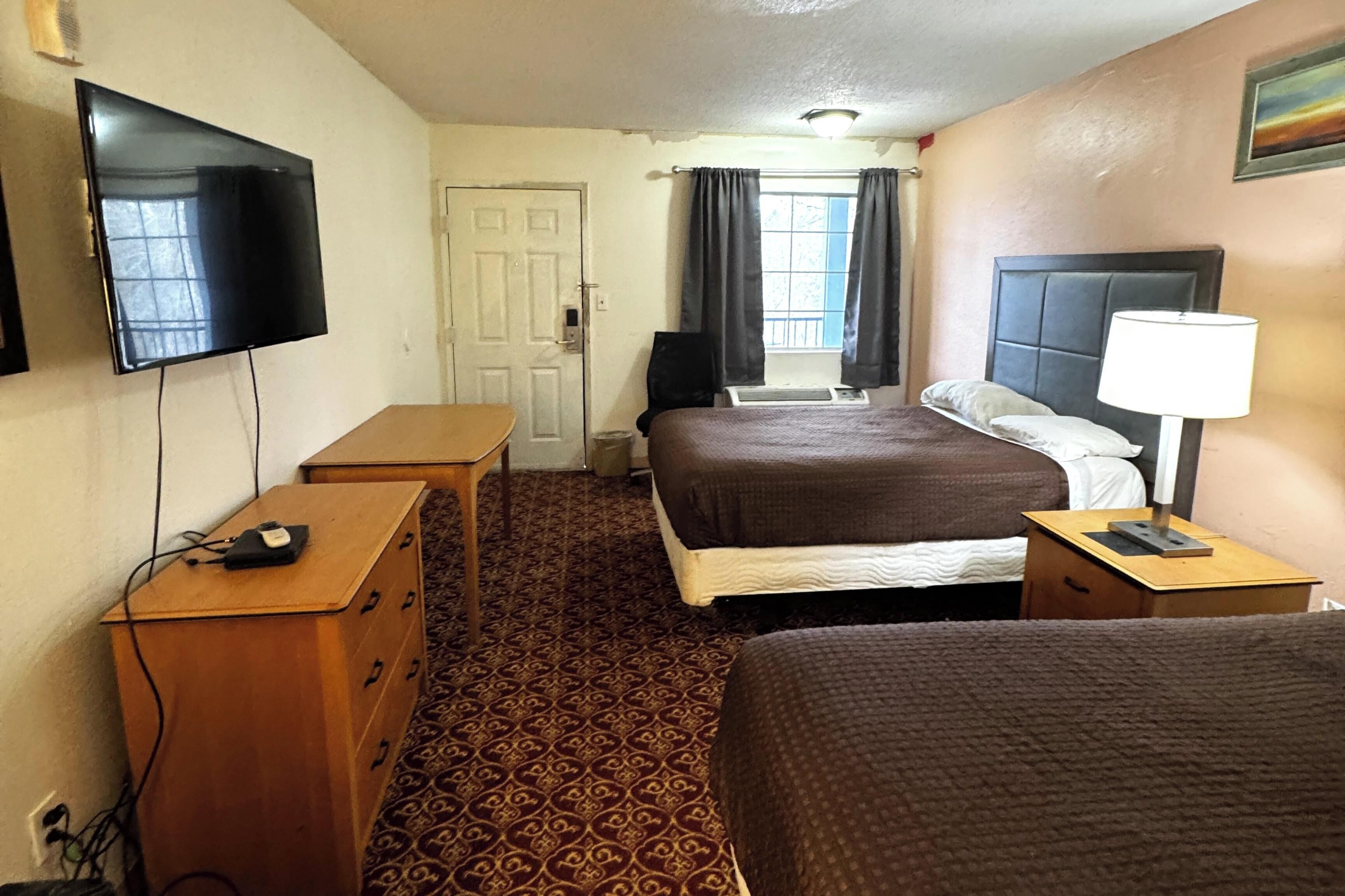 A hotel room with a bed, a TV, a desk, and a dresser.