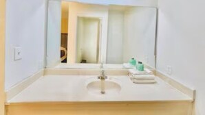 A bathroom with a white sink, a mirror, and toiletries on the counter.