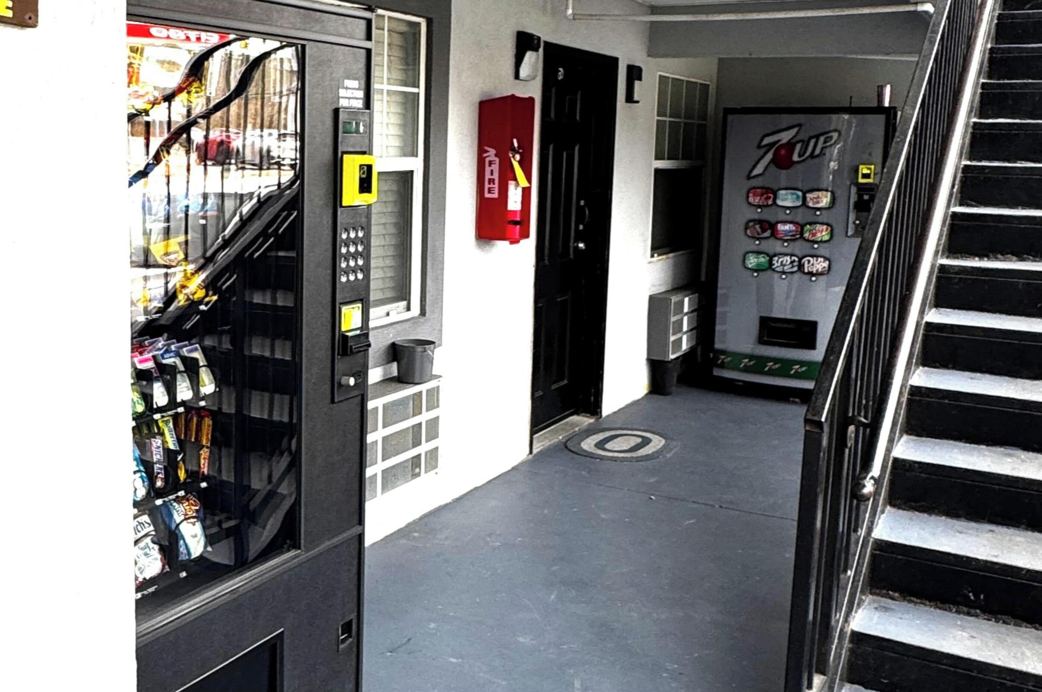 En korridor med en automattankstation, en brandsläckare och ett kylskåp med 7UP-läsk.