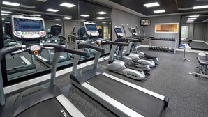 A gym with multiple treadmills, a weight bench, and dumbbells.