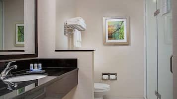 A modern bathroom with a black countertop sink, a white toilet, and a glass shower enclosure.