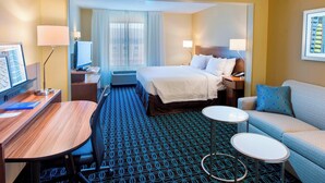 A hotel room with a bed, a desk, a chair, a sofa, and a small table.