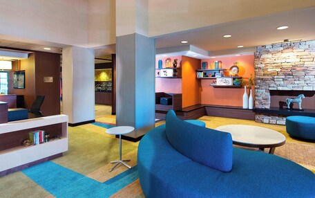 A modern lobby with a blue sofa, a small round table, and a fireplace with a stone wall.
