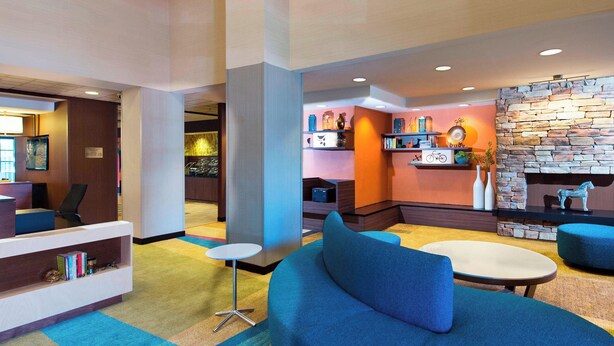 A modern lobby with a blue sofa, a small round table, and a fireplace with a stone wall.