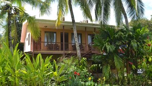 A two-story building with a balcony, surrounded by lush tropical vegetation. - Hotel Diuwak (Bahía Ballena)