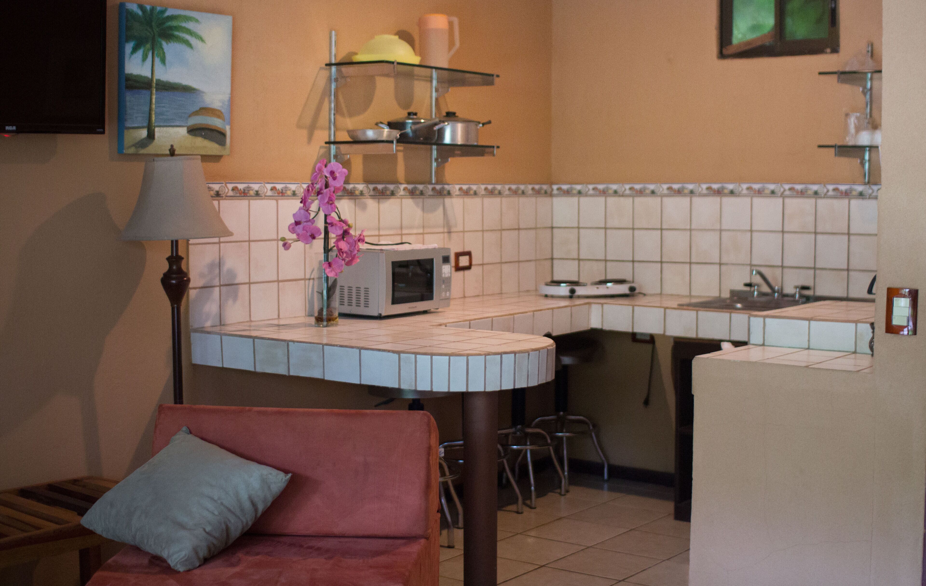 A compact kitchen with a microwave, a sink, and a small dining area with a chair and a table.
